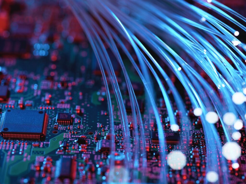 Glasfasern fließen durch Leiterplatten von einem Laptop – symbolisiert innovative Lösungen und IO-Link Produkterfolg.