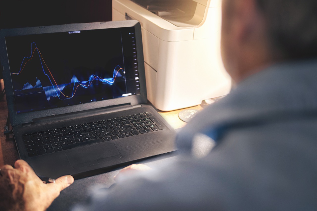 Mann sitzt am Schreibtisch vor Laptop – führt elektrische Prüfung von IO-Link Geräten durch.